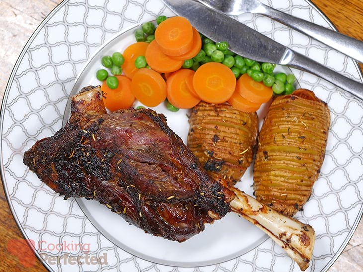 Air fried lamb shanks served with potatoes, peas, and carrots.