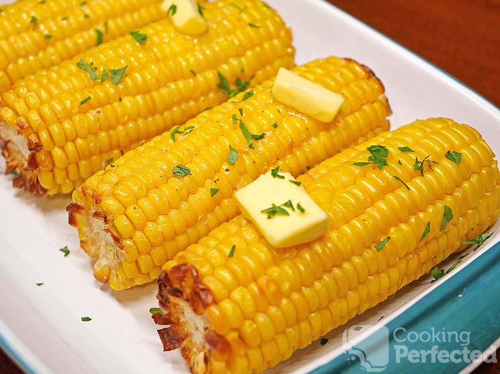 Air-fried corn on the cob garnished with butter and chopped parsley