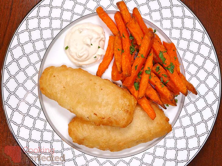 Battered fish served with tartar sauce and sweet potato fries